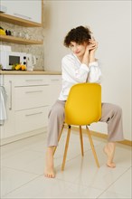 Relaxed woman sits on chair in the kitchen