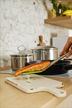 Closeup view of fried salmon steak on a spatula over the serving board in the kitchen