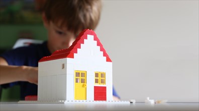 Boy builds a house with building blocks (with free space for text)