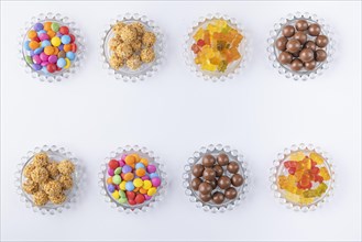 Sweets on small glass plates in two rows on a white background photographed from above, copy room