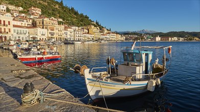 Quiet harbour with boats in front of picturesque coastal town and mountains in the background,