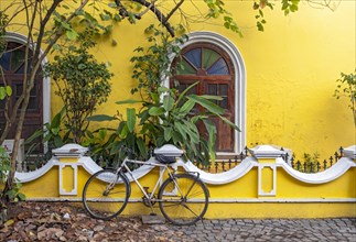 Street scene with bicycle in front of yellow house, Fort Kochi, Cochin, Kerala, India, Asia
