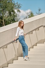 Woman standing with her back against railing on stairs spreading arms
