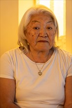 Portrait of older adult woman with gray hair looking at the camera with sad expression on her face