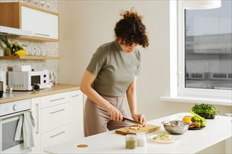 Young woman slicing fresh champignon in the kitchen on wooden cutting board