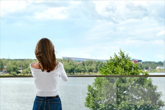 Back view of woman standing on the observation deck and enjoying amazing view of the city river