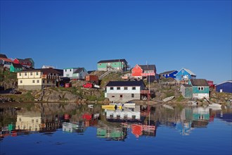 Colourful houses reflected in the calm waters of the fjord, Maniitsoq, Greenland, Denmark, North