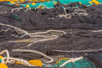 Closeup of large black and green fishing nets with yellow floats laid out on ground to dry in South