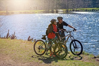 Mountain bikers take a break at a lake in the Palatinate Forest near St. Martin