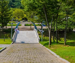 Brick walkway down hill to concrete bridge over ravine at Independence Hall park in Cheonan, South