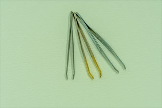 Three pair of tweezers side by side isolated on light textured background