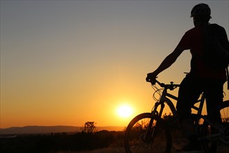Symbolic image: Silhouette of a mountain biker on a warm summer evening