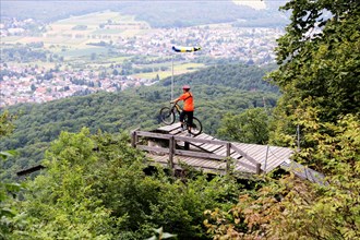 Mountain biker stands on the launch ramp for hang-gliders below the Melibokus and looks out over