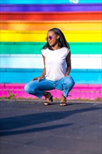 Young casual african woman squatting on an urban park posing with sunglasses