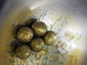 A close-up of golden sprayed edible chocolate balls used for cake decoration