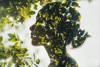 Calming image of a woman in double exposure surrounded by delicate foliage, symbolic image for