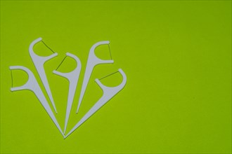 Closeup of white of plastic flossing picks on green background