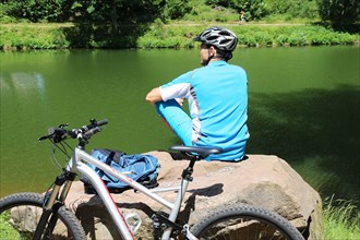 Symbolic image: Mountain biker taking a break at a lake (Edenkobener Tal, Palatinate Forest)