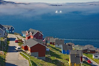Colourful houses in front of a foggy fjord with icebergs, Qaqortoq, Greenland, Denmark, North