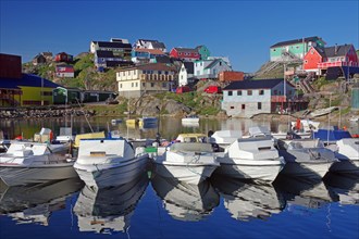 Pleasure boats and colourful houses are reflected in the calm water, Maniitsoq Harbour, Greenland,