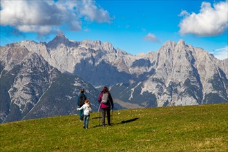 Hiking with children in Seefeld, Tyrol: Family hiking across an alpine meadow, with the Wetterstein