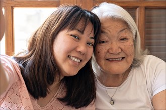 Portrait of mother and daughter. Japanese elderly woman with white hair and daughter smiling taking