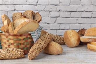 A woven bread basket filled with a selection of bread on a wooden table