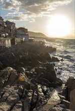 Sea water crashes against the cliffs of the rugged coastline in the town of Cefalu, Sicily, Italy,