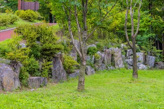 Wall of large boulders in lush urban public park with walking path going uphill in background in