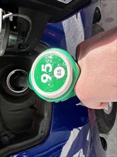 Detail of a person's hand pouring gas into a car at a gas station. refueling the car's tank