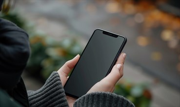 Female hands holding a black smartphone with blank screen. Close up shot AI generated