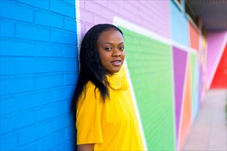 Portrait with copy space of a cool african woman leaning on a colorful wall and looking at camera