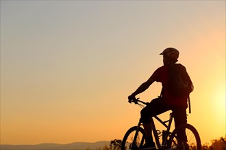 Symbolic image: Silhouette of a mountain biker on a warm summer evening