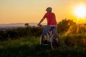 Symbolic image: Mountain biker enjoying the view at sunset