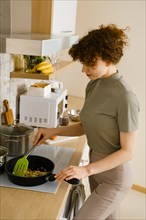 Woman stirring vegetables in a frying pan while making sauce for pasta