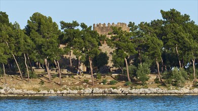 Old stone castle surrounded by pine trees on the Mediterranean coast, Gythio, Mani, Peloponnese,