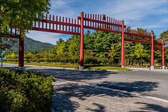 Large red wooden gate across four lane road in public park in South Korea