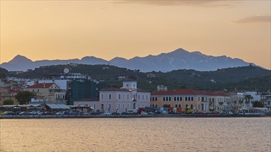 Coastline with buildings and mountains during a colourful sunset, Snow-covered Taygetos Mountains,