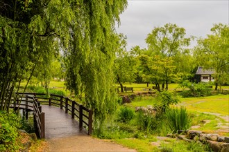 Peaceful landscape of wooden footbridge and benches in a public park on an overcast rainy morning