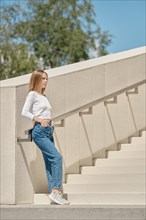 Woman standing on stairs in profile with her hands in pockets