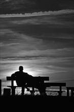 Silhouette against the sun, couple on a bench by the Baltic Sea, Ahrenshoop, Darss,