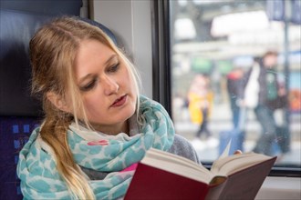 Young woman reading a book on the train