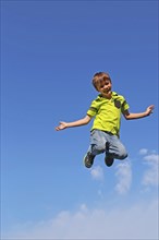 Symbolic image: Boy jumping into the air, blue sky in the background