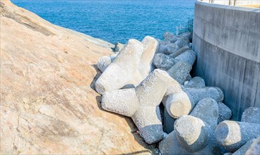 Tetrapods stacked between concrete pier and rocky shore at ocean port in South Korea