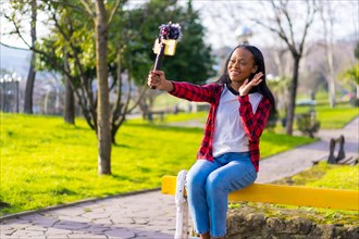 Young african vlogger records a video with a mobile in a park