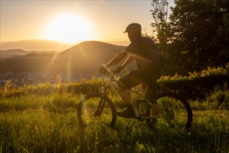 Mountain biker in the low evening sun looking towards the small town of Dahn in the Palatinate