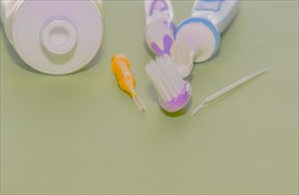 Closeup of toothbrushes and flossing picks next to opened tube of toothpaste