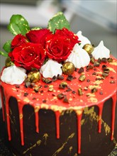 Luxurious cake with red dripping icing, roses, chocolates, and gold accents