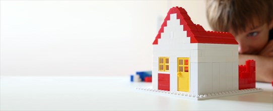 Boy builds a house with building blocks (with free space for text)