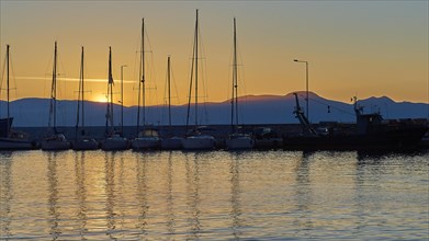 Yachts in the harbour at sunset with mountains in the background and evening sky, Gythio, Mani,